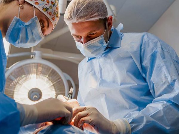 Blepharoplasty plastic surgery operation for modifying the eye region of the face in medical clinic. 2 doctors do plastic cosmetic operation for woman. Surgeon makes an incision with a surgical knife